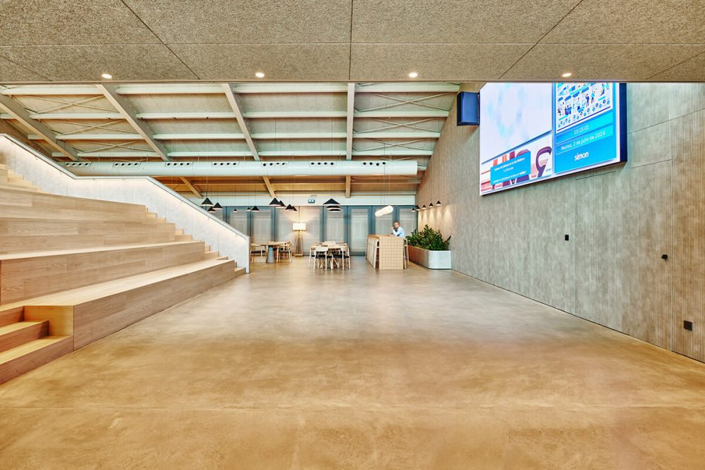 Espacio central corporativo con grada y arquitectura industrial reformada